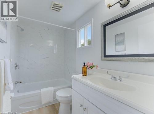 Bathroom featuring a white vanity with integrated sink, chrome fixtures, and a framed mirror - 603 Pinerow Crescent Unit# B, Waterloo, ON 