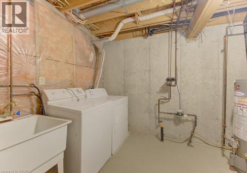 Utility area featuring a laundry sink, exposed concrete foundation wall, and visible overhead joists - 603 Pinerow Crescent Unit# B, Waterloo, ON 