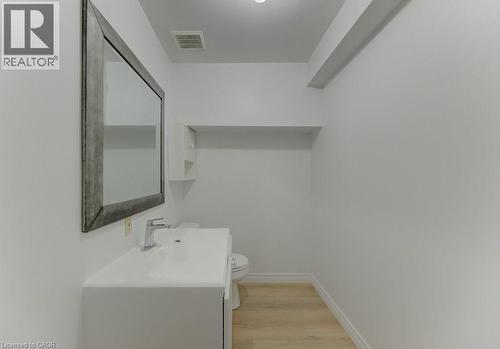 Contemporary powder room featuring a white vanity with integrated sink, chrome faucet, and a large framed mirror - 603 Pinerow Crescent Unit# B, Waterloo, ON 