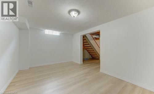 Finished lower-level room featuring light wood-finish flooring, white painted walls, and an overhead flush-mount light fixture - 603 Pinerow Crescent Unit# B, Waterloo, ON 