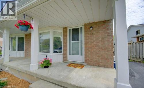 Brick exterior with a covered porch featuring white support columns and a white screen door - 603 Pinerow Crescent Unit# B, Waterloo, ON 