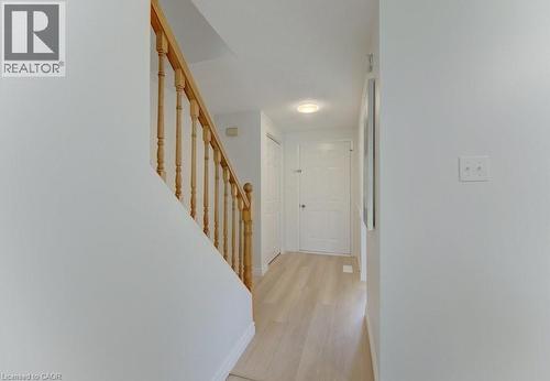 Hallway featuring wood-finish flooring, white walls, a staircase with wood balusters and handrail, and a flush-mount ceiling light - 603 Pinerow Crescent Unit# B, Waterloo, ON 