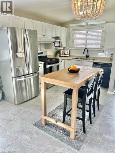 Kitchen featuring stainless steel refrigerator, white cabinetry, a light wood-finish island, and gray tile flooring - 241 Thorner Drive, Hamilton, ON - Indoor Photo Showing Kitchen