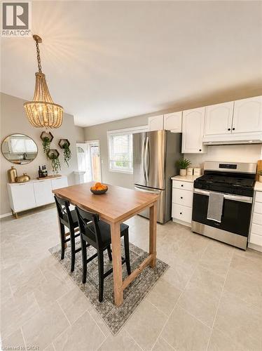 Open-concept kitchen featuring light-toned tile flooring, white cabinetry, and stainless steel appliances - 241 Thorner Drive, Hamilton, ON - Indoor