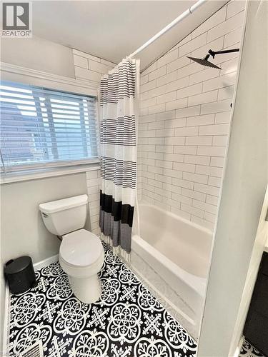 Bathroom featuring a combination tub and shower with white subway tile surround, matte black rainfall showerhead, and a patterned floor tile - 241 Thorner Drive, Hamilton, ON - Indoor Photo Showing Bathroom