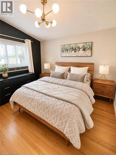 Spacious interior featuring wood-finish flooring, a contemporary chandelier, a window with horizontal blinds, and a built-in black dresser - 241 Thorner Drive, Hamilton, ON - Indoor Photo Showing Bedroom