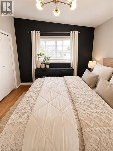 Bedroom featuring a contemporary ceiling fixture, a window with blinds and drapes, and wood-finish flooring - 241 Thorner Drive, Hamilton, ON - Indoor Photo Showing Bedroom