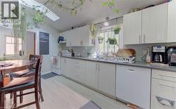 Functional kitchen featuring light-toned cabinetry, a skylight, a double-basin sink, and a built-in dishwasher - 