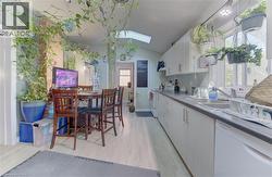 Galley kitchen featuring light-finish cabinetry, dark countertops, and stainless steel sink - 