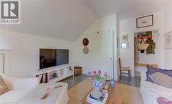 Interior space featuring a vaulted ceiling, wood-finish flooring, white walls, and a built-in entryway bench with shelving and hooks - 
