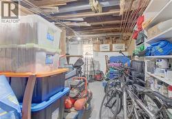 Unfinished basement space featuring exposed ceiling joists and support beams, dedicated storage shelving, and a small basement window - 