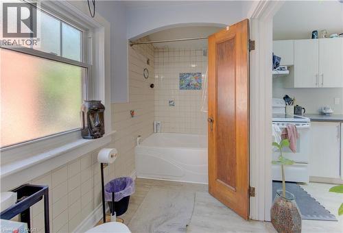 Main floor bathroom featuring a tiled shower/tub combination, frosted window, and wood-finish door - 48 Breithaupt Street, Kitchener, ON - Indoor Photo Showing Bathroom