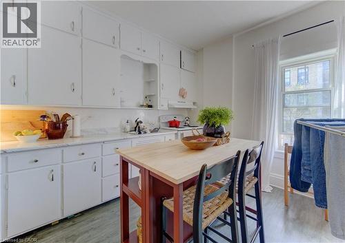 Upper unit kitchen featuring extensive white cabinetry, light-toned countertops, and wood-finish flooring - 48 Breithaupt Street, Kitchener, ON - Indoor
