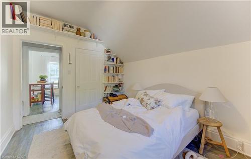 Upper bedroom featuring sloped ceilings, wood-finish flooring, built-in shelving, white paneled doors, and an additional doorway to an adjacent room - 48 Breithaupt Street, Kitchener, ON - Indoor Photo Showing Bedroom