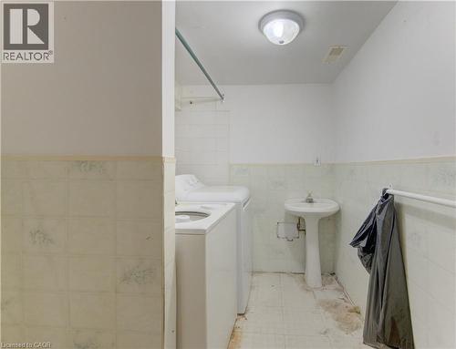 Shared laundry space featuring a pedestal sink, a ceiling-mount light fixture, and tiled flooring - 48 Breithaupt Street, Kitchener, ON - Indoor Photo Showing Laundry Room