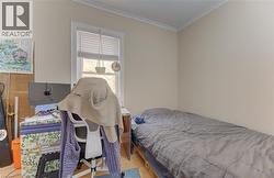 Room featuring light-toned walls, crown molding, and wood-finish flooring - 