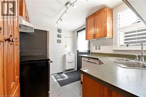 Kitchen featuring wood-finish cabinetry, solid surface countertops, a double basin stainless steel sink, and a built-in dishwasher - 23 Britannia Avenue, Hamilton, ON - Indoor Photo Showing Kitchen With Double Sink