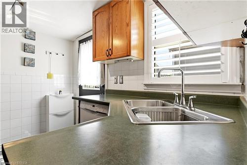 Kitchen featuring a stainless steel double-basin sink, chrome faucet, and integrated dishwasher - 23 Britannia Avenue, Hamilton, ON - Indoor Photo Showing Kitchen With Double Sink