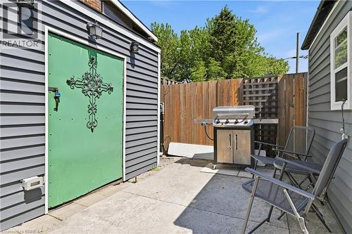 Private concrete patio area featuring a decorative green door with wrought iron detailing - 23 Britannia Avenue, Hamilton, ON - Outdoor