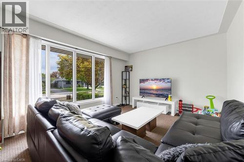 Bright living area featuring a large picture window, neutral wall paint, and textured carpet flooring - 46 Beaconsfield Drive, Hamilton, ON - Indoor Photo Showing Living Room