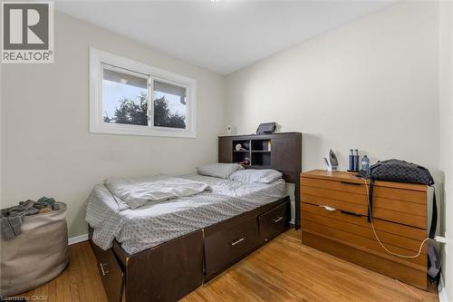 Bedroom featuring light-toned walls, wood-finish flooring, and a white-framed window - 46 Beaconsfield Drive, Hamilton, ON - Indoor Photo Showing Bedroom