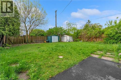 Expansive grassy yard featuring a wood fence, mature trees, a small storage shed, and a metal storage shed - 46 Beaconsfield Drive, Hamilton, ON - Outdoor
