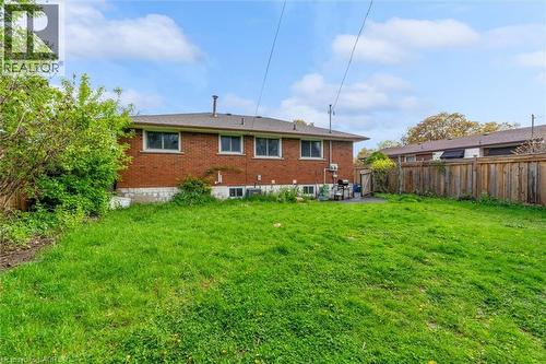 Expansive rear yard featuring green lawn, mature perimeter fencing, and a red brick exterior with multiple windows - 46 Beaconsfield Drive, Hamilton, ON - Outdoor