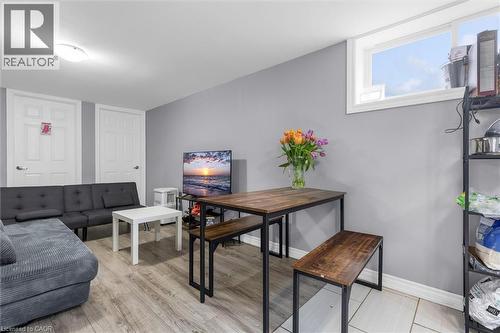 Open-concept living space featuring wood-finish flooring, a contemporary dining table with benches, and a high-set window - 46 Beaconsfield Drive, Hamilton, ON - Indoor