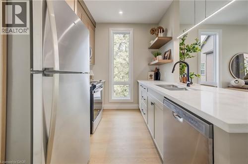Modern kitchen featuring stainless steel appliances, light wood-finish flooring, white countertops, and a black gooseneck faucet - 210 Heritage Drive Unit# Main, Kitchener, ON - Indoor Photo Showing Kitchen With Double Sink