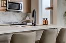 Modern kitchen featuring a seamless undermount sink with a matte black faucet, light wood-finish cabinetry, stainless steel microwave, and a light-toned countertop with a matching backsplash - 210 Heritage Drive Unit# Main, Kitchener, ON  - Indoor Photo Showing Kitchen 