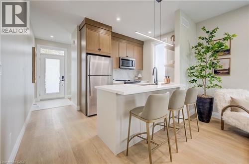 Contemporary kitchen featuring light wood-finish flooring, white countertops, stainless steel appliances, and wood cabinetry - 210 Heritage Drive Unit# Main, Kitchener, ON - Indoor Photo Showing Kitchen With Upgraded Kitchen