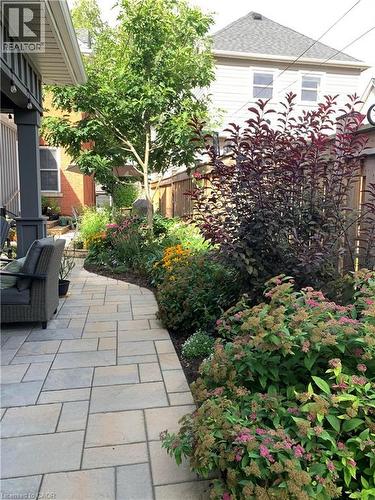 Landscaped side yard featuring a paver walkway, mature plantings, and a covered patio area - 546 Hurd Avenue, Burlington, ON - Outdoor With Deck Patio Veranda