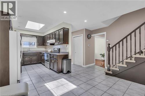Kitchen featuring stainless steel electric range, freestanding refrigerator, a skylight, light countertops, and light tile patterned floors - 146 Bechtel Drive, Kitchener, ON - Indoor Photo Showing Kitchen