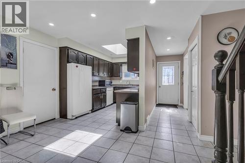 Kitchen featuring white appliances, light countertops, a skylight, light tile patterned floors, and dark wood finish cabinets - 146 Bechtel Drive, Kitchener, ON - Indoor Photo Showing Kitchen