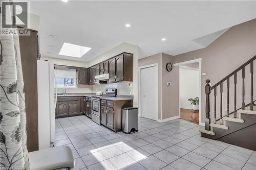 Kitchen featuring electric stove, freestanding refrigerator, light countertops, dark wood finish cabinets, and light tile patterned floors - 146 Bechtel Drive, Kitchener, ON - Indoor Photo Showing Kitchen