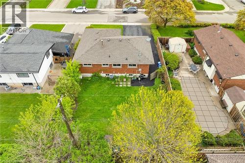 Rear exterior featuring a sizable backyard with a manicured lawn, a paved patio area, and mature trees - 46 Beaconsfield Drive, Hamilton, ON - Outdoor With View