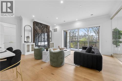 Spacious living area featuring light wood-finish flooring, a full-height dark marble-look accent wall, and recessed ceiling lighting - 2 Arbourvale Common Unit# 209, St. Catharines, ON - Indoor Photo Showing Living Room