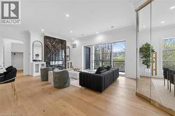 Spacious living area featuring a dark marble-clad fireplace, wood-finish flooring, recessed lighting, crown molding, and large glass sliding doors opening to an exterior balcony - 