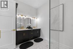 Bathroom featuring a dual vanity with black cabinetry, brass hardware, and a white countertop - 