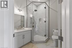 Modern bathroom featuring a glass-enclosed corner shower with full-height tile surround and an integrated niche - 
