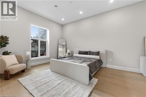 Spacious bedroom with light wood-finish flooring and a bright window featuring a white trim - 2 Arbourvale Common Unit# 209, St. Catharines, ON - Indoor Photo Showing Bedroom