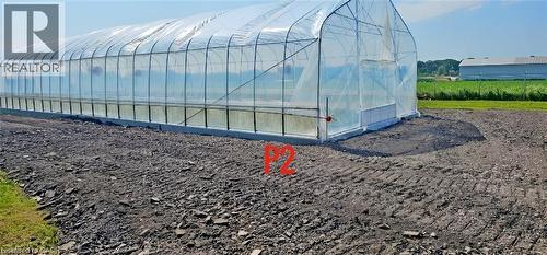 Long, clear-span greenhouse structure with a sturdy frame, translucent covering, and a concrete foundation - 96 Second Road E, Stoney Creek, ON 