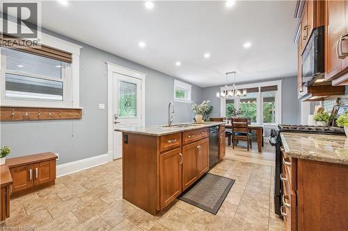Open-concept kitchen featuring an island with a built-in sink, granite countertops, tile flooring, recessed lighting, and wood cabinetry - 310 Kitchener Road, Cambridge, ON - Indoor Photo Showing Kitchen