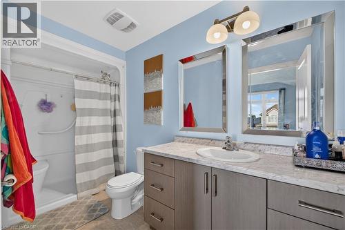 Bathroom featuring a shower-tub combination, a vanity with an integrated sink, a light-toned countertop, and dual framed mirrors - 32 Ashberry Place, St. Thomas, ON 