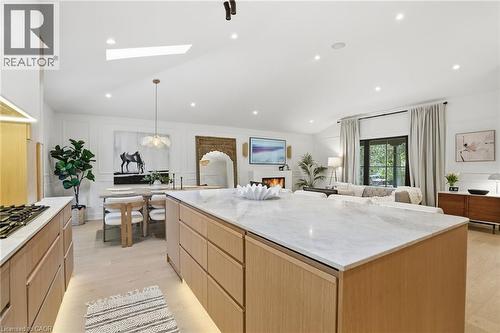 Expansive open-concept living space featuring a central kitchen island with a stone countertop, light wood-finish cabinetry, a built-in gas range, and recessed lighting - 345 Rankin Drive, Burlington, ON - Indoor Photo Showing Kitchen With Upgraded Kitchen