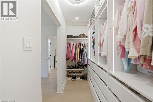Custom closet system featuring extensive built-in cabinetry, integrated lighting, recessed ceiling lighting, wood-finish flooring, and a flush-mounted light switch panel - 345 Rankin Drive, Burlington, ON - Indoor