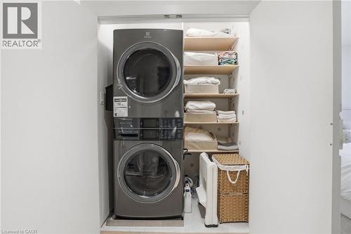 Dedicated laundry closet featuring a stacked washer and dryer unit, multiple adjustable shelving units, and a built-in utility hook - 345 Rankin Drive, Burlington, ON - Indoor Photo Showing Laundry Room