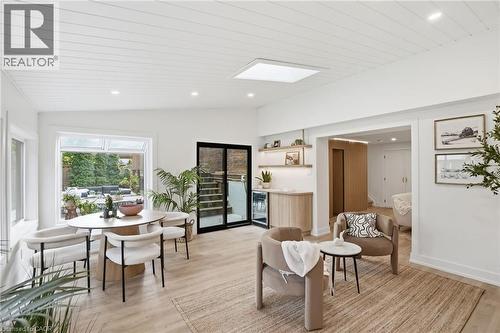 Open-concept living space with light wood-finish flooring, white shiplap ceiling, recessed lighting, and a large window overlooking exterior greenery - 345 Rankin Drive, Burlington, ON - Indoor