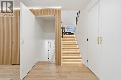 Hardwood-look flooring throughout, featuring a staircase with integrated step lighting and a black metal handrail - 345 Rankin Drive, Burlington, ON - Indoor Photo Showing Other Room