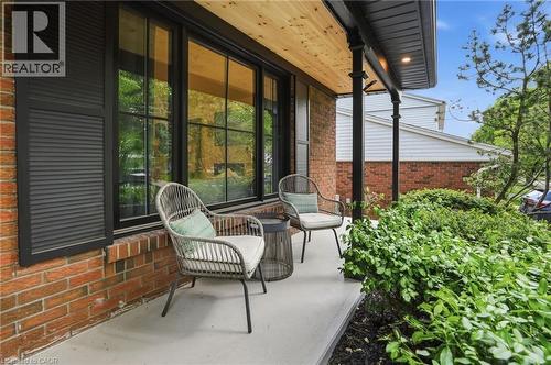 Brick facade featuring a covered porch with a wood-finish ceiling, recessed lighting, and dark columns - 345 Rankin Drive, Burlington, ON - Outdoor With Exterior